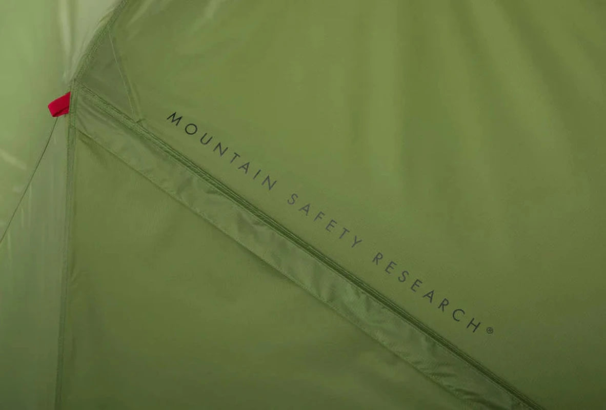 Närbild av olivgrönt tälttyg med tryckt Mountain Safety Research-logotyp