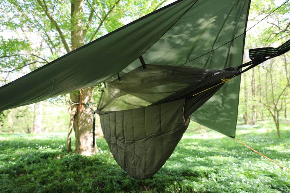 Mörkgrön tarp installerad som skydd över hängmatta i solig skog