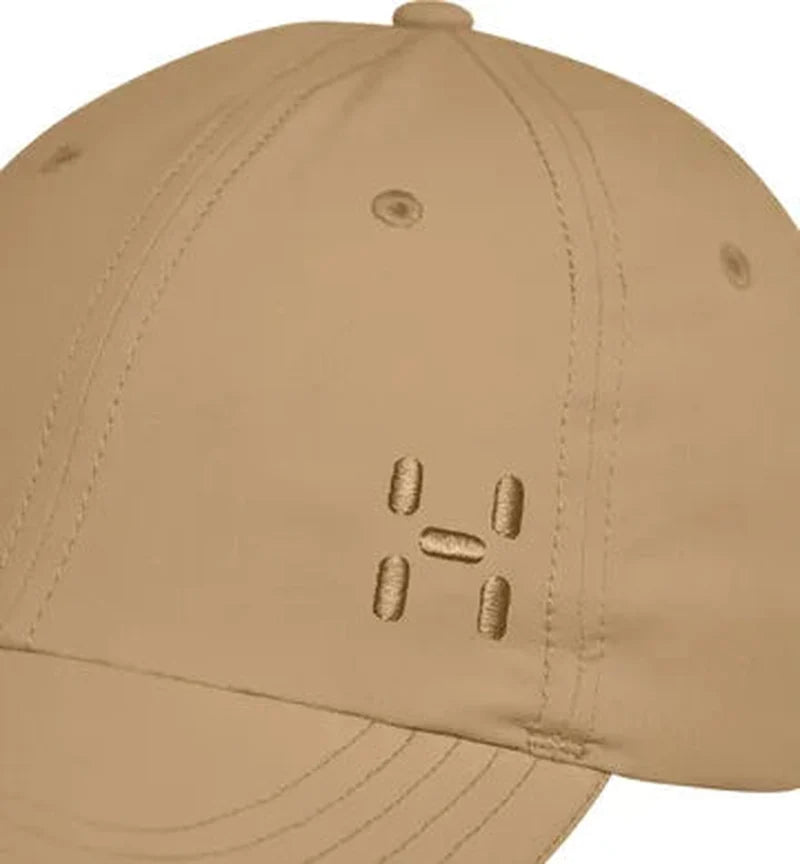 Närbild på beige Haglöfs keps som visar tygdetaljer och H-logo