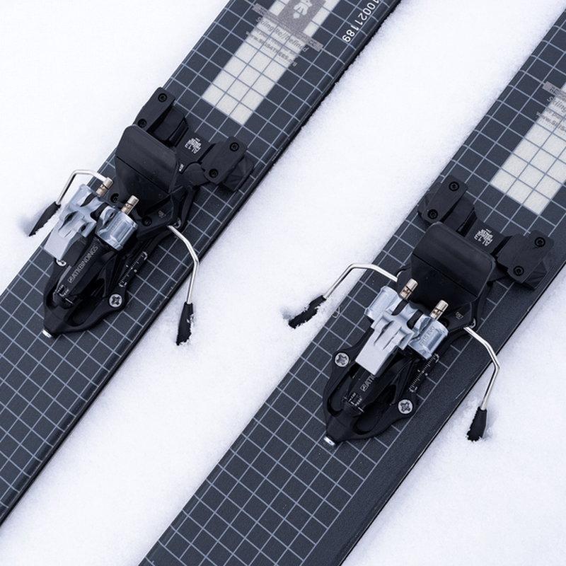 Svarta ATK-bindingar med silverdetaljer och friktionsstöd på skidor i snö
