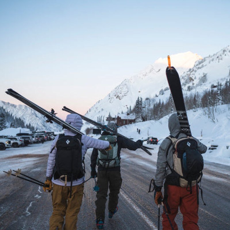 Skidåkare med beige och svart Dawn Patrol 25 ryggsäck på snöväg
