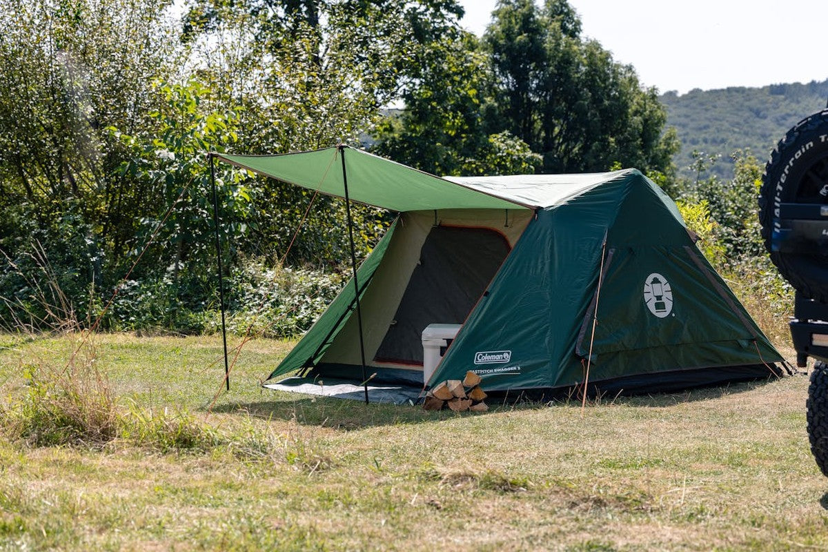 Fastpitch Swagger 3 campingtält i naturmiljö med kylkasse och brasa vid ingången