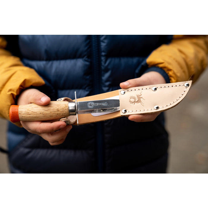 Barn håller Brusletto Scoutkniv i beige lädersheath med silvernitar