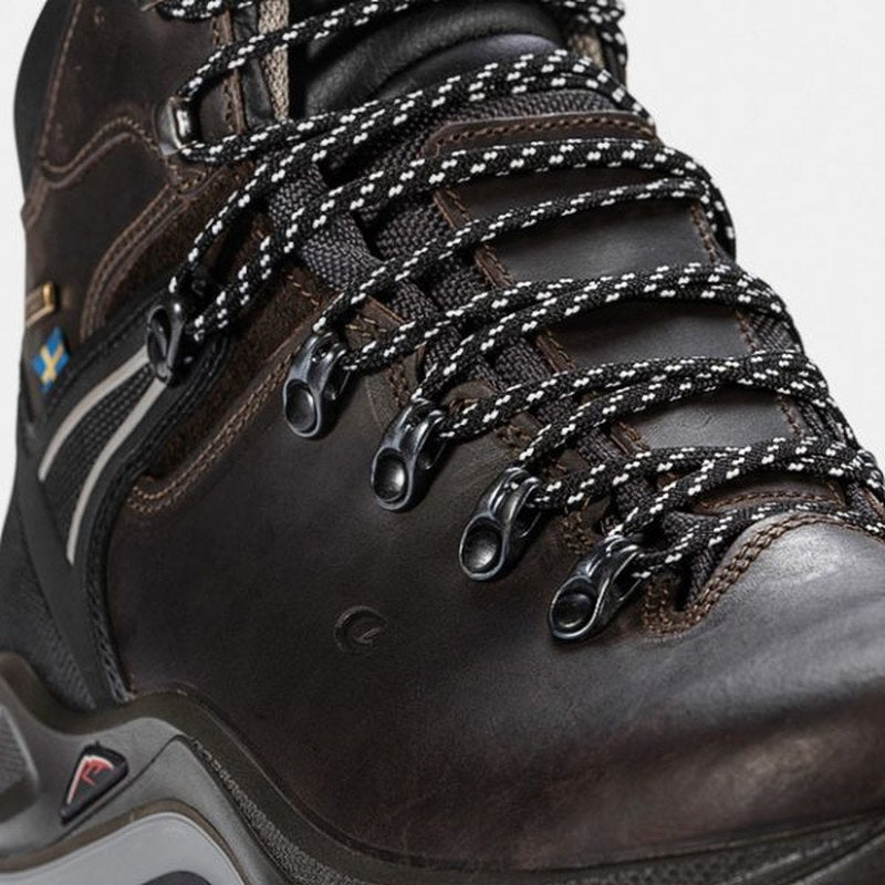 Detalj av mörkt läder och flagg-emblem på vandringssko