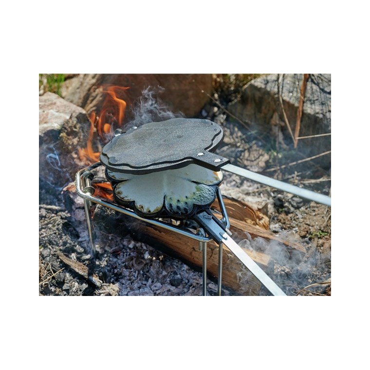 Gjutjärnsvåffeljärn med hjärtformade våfflor över öppen eld