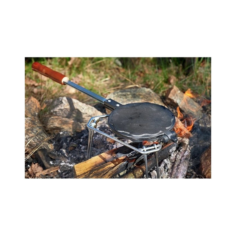 Våffeljärn i gjutjärn på grillstativ vid bål